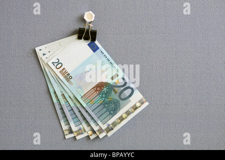 Several 20 euro notes hanging in a bulldog clip from a board covered in blue fabric Stock Photo