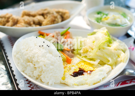 Delicious set of lunch. Chinese food with rice, egg, cabbage vegetable ,fried chicken and soup on the table.