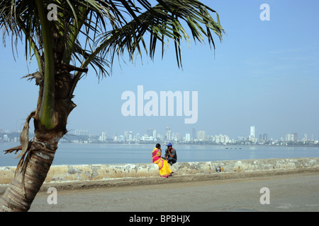 Young couple sit by back bay on the Arabian Sea, Netaji Subhash Chandra Road (Marine Drive) in the Churchgate district of Mumbai Stock Photo