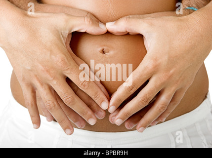 Pregnant women wrap her arms around the belly in the form of the heart. Isolated on white. Stock Photo