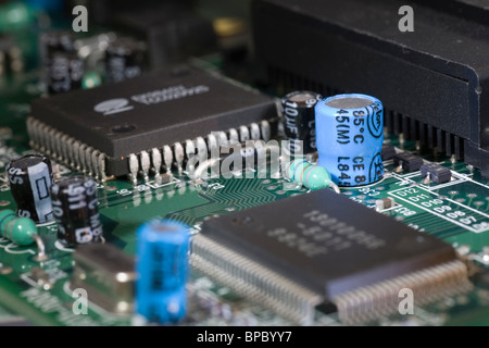 Electrolytic capacitor on an electronic circuit board next to other components such as a diode and resistor. Stock Photo