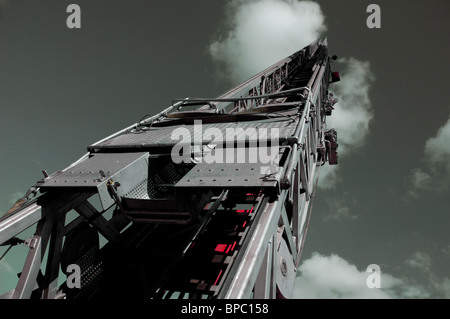Steel fire truck ladder leading up into gray sky