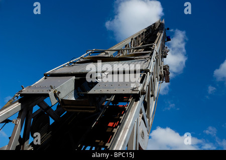 Steel fire truck ladder leading up into blue sky