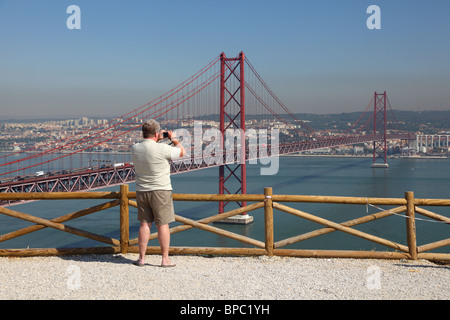 Tourist taking pictures of the Ponte 25 de Abril - Suspension bridge over the Tagus river in Lisbon, Portugal Stock Photo