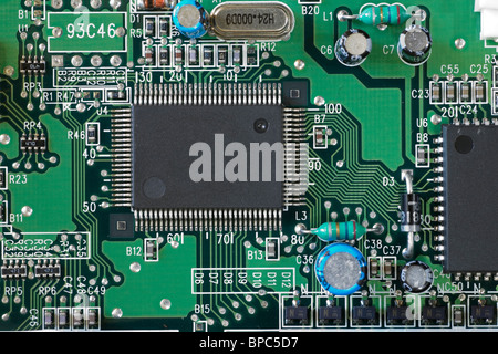 Multi pin micro chip surrounded by electronic components on a circuit board Stock Photo
