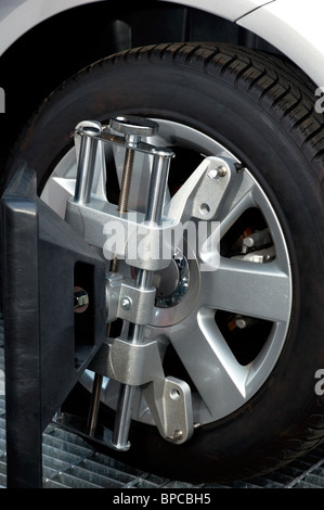 Car wheel fixed with computerized wheel alignment machine clamp. Closeup of repairshop equipment. Stock Photo