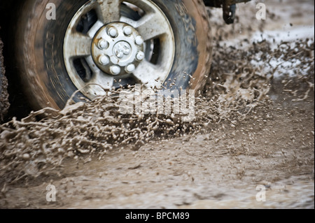 An image of a truck wheel and tire spinning through a mud hole. Stock Photo