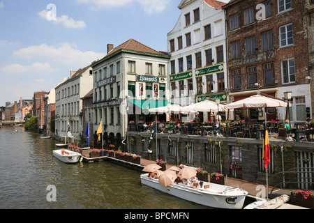 Graslei Site, Ghent, East Flanders, Belgium. Tourists in sightseeing boat on River Leie with quayside cafe in historic district Stock Photo