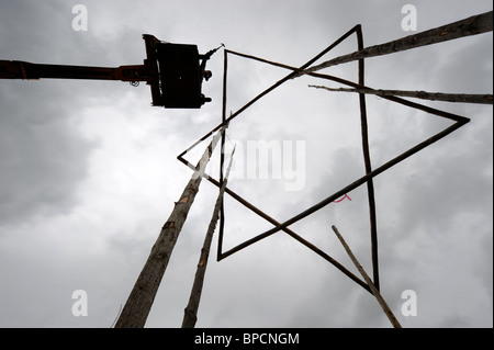 A scaffolder erects a timber star near The Pyramid Stage at the Glastonbury Festival site Pilton UK Stock Photo