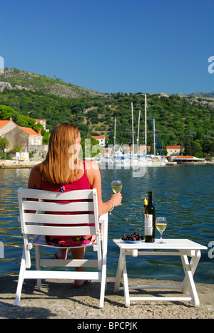 ZATON, near DUBROVNIK, CROATIA. A woman on holiday drinking Croatian wine and looking out over Zaton bay. Stock Photo