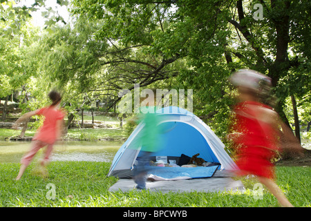 Kids chasing each other around a tent while camping Stock Photo