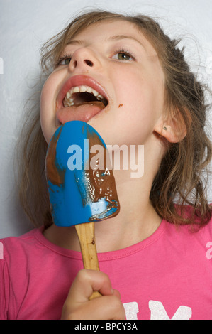 Young girl licking chocolate icing from a spoon Stock Photo