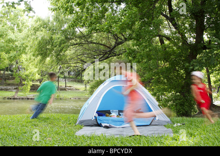 Kids chasing each other around a tent while camping Stock Photo