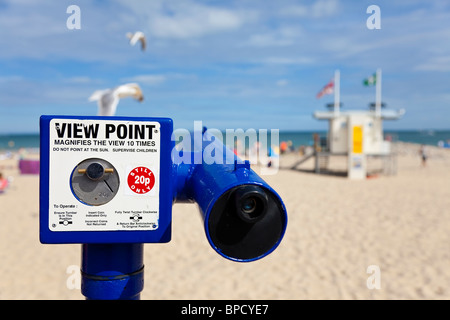 A coin operated telescope viewpoint on a classic British beach during the summer with seagulls flying past Stock Photo