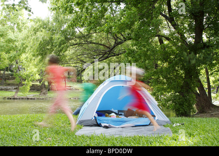 Kids chasing each other around a tent while camping Stock Photo