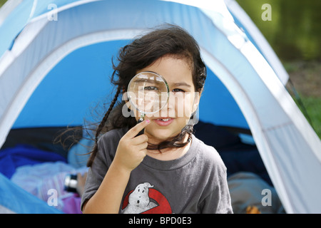 Girl looking at camera through magnifying glass Stock Photo