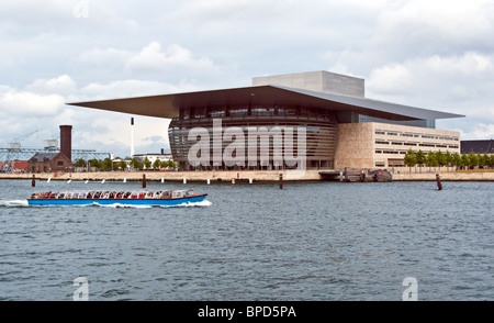 The Royal Opera House on Holmen in Copenhagen Denmark with a harbour cruising vessel passing by. Stock Photo