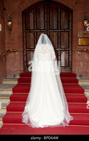 Bride standing on steps showing the back of her wedding dress Stock Photo