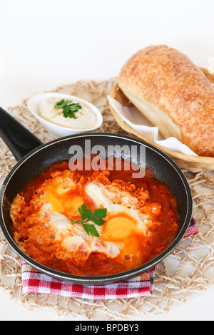 Shakshouka a spicy Middle Eastern dish consisting of poached or fried eggs cooked in a sauce of tomatoes bell peppers and onions Stock Photo