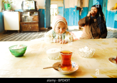 Azerbaijan, Xinaliq, view of traditional tea cups and crockery in foreground with grandparent and baby boy Stock Photo