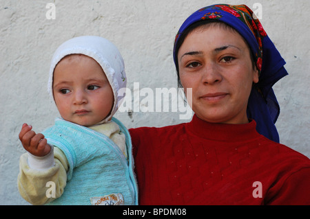 Azerbaijan, Xinaliq, close-up portrait of mother wearing scarf and carrying her baby Stock Photo