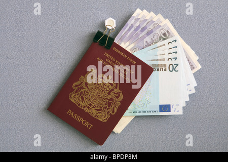 A uk passport containing sterling and euro notes hanging from a bulldog clip Stock Photo