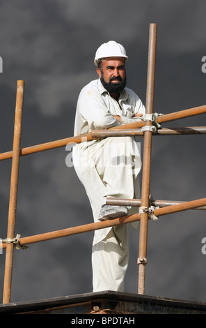 A construction worker on a scaffolding in front of a dark cloud of smoke, Dubai, United Arab Emirates Stock Photo