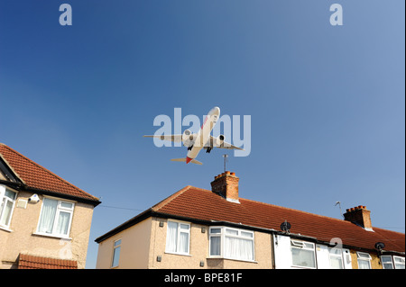 Airplane flying low over house prior to landing Stock Photo