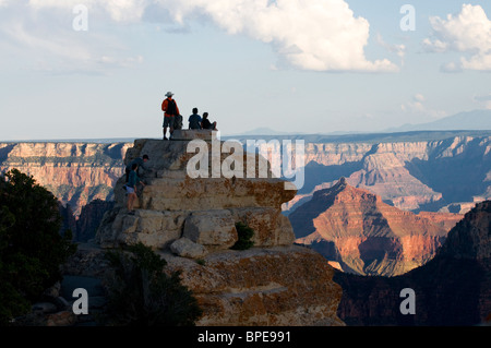 Tourists at bright angel point view perched on rocks overlooking the north rim of the Grand Canyon Stock Photo