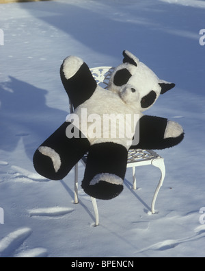 Panda teddy bear sitting on a chair in the snow Stock Photo
