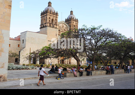 Historic Church of Santo Domingo with gardens, trees, people and street in the foreground.  Oaxaca, Mexico Stock Photo