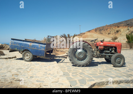 Red tractor with rear end of blue pickup truck used as trailer Stock Photo