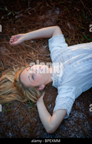 Young woman lying in field daydreaming Stock Photo