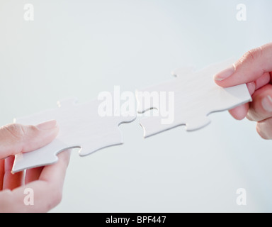 Hands connecting jigsaw puzzle pieces Stock Photo