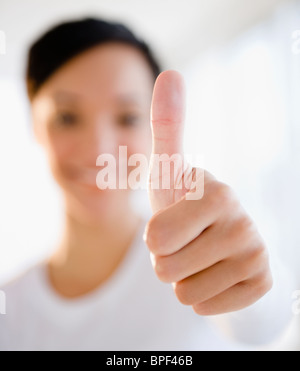 Mixed race woman giving thumbs up sign Stock Photo