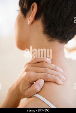 Mixed race woman rubbing neck and shoulder Stock Photo