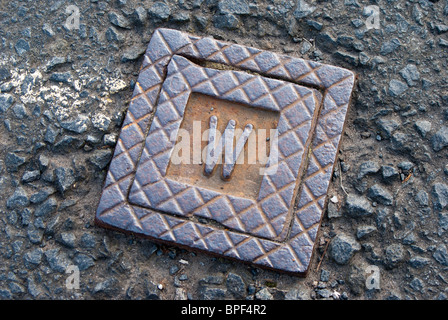 Public utilities delivery of services under road surface - water supply for factory, stop tap cover Stock Photo