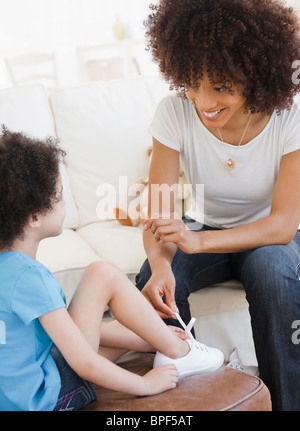 Mother tying shoe of daughter Stock Photo