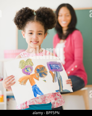 Proud student holding painting in classroom Stock Photo