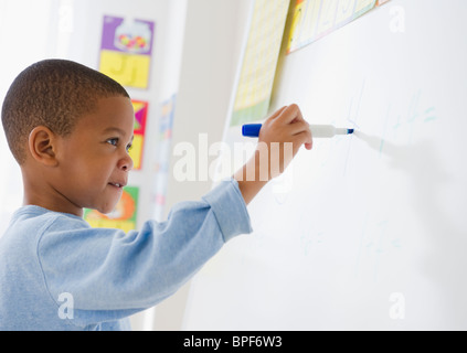 African American boy writing on white board Stock Photo