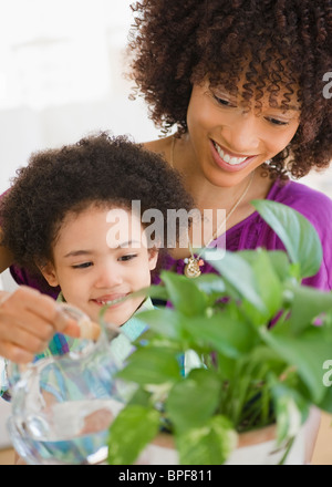 Mother and daughter watering potted plant Stock Photo