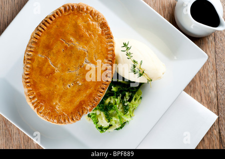 Traditional british pub food - big pie with mash and vegetables Stock Photo