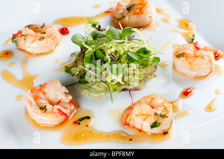 Sauté prawns with chill, ginger and coriander with a nest of baby leaf salad Stock Photo