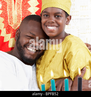 African American father hugging son in traditional clothing Stock Photo