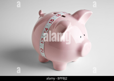 Tape measure around the middle of a piggy bank Stock Photo