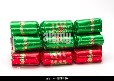 A stack of green and red foil Christmas crackers on a white background Stock Photo