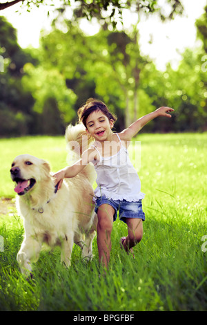 Young girl with golden retriever running outdoors Stock Photo