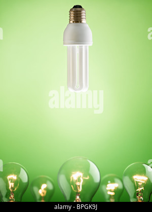 fluorescent lightbulb over large group of tungsten lights on green background. Vertical shape, copy space Stock Photo