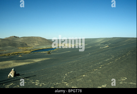 A tourist filming Waw an Namus Crater in the southern region of Libya, near to the geographic center of the Sahara desert. Stock Photo