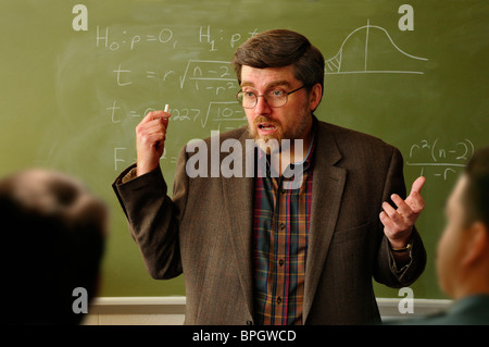 Math professor or teacher interacting with students in a classroom, Statistical formula on chalkboard in background. Stock Photo